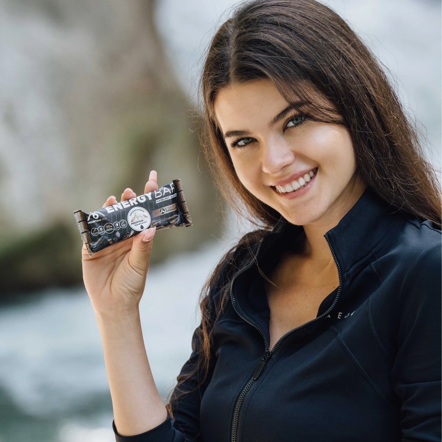 Nainen pitämässä energiapatukkaa kädessään luonnossa. Mountaindrop energiapatukka sopii arkeen ja treeneihin täydellisenä välipalana.