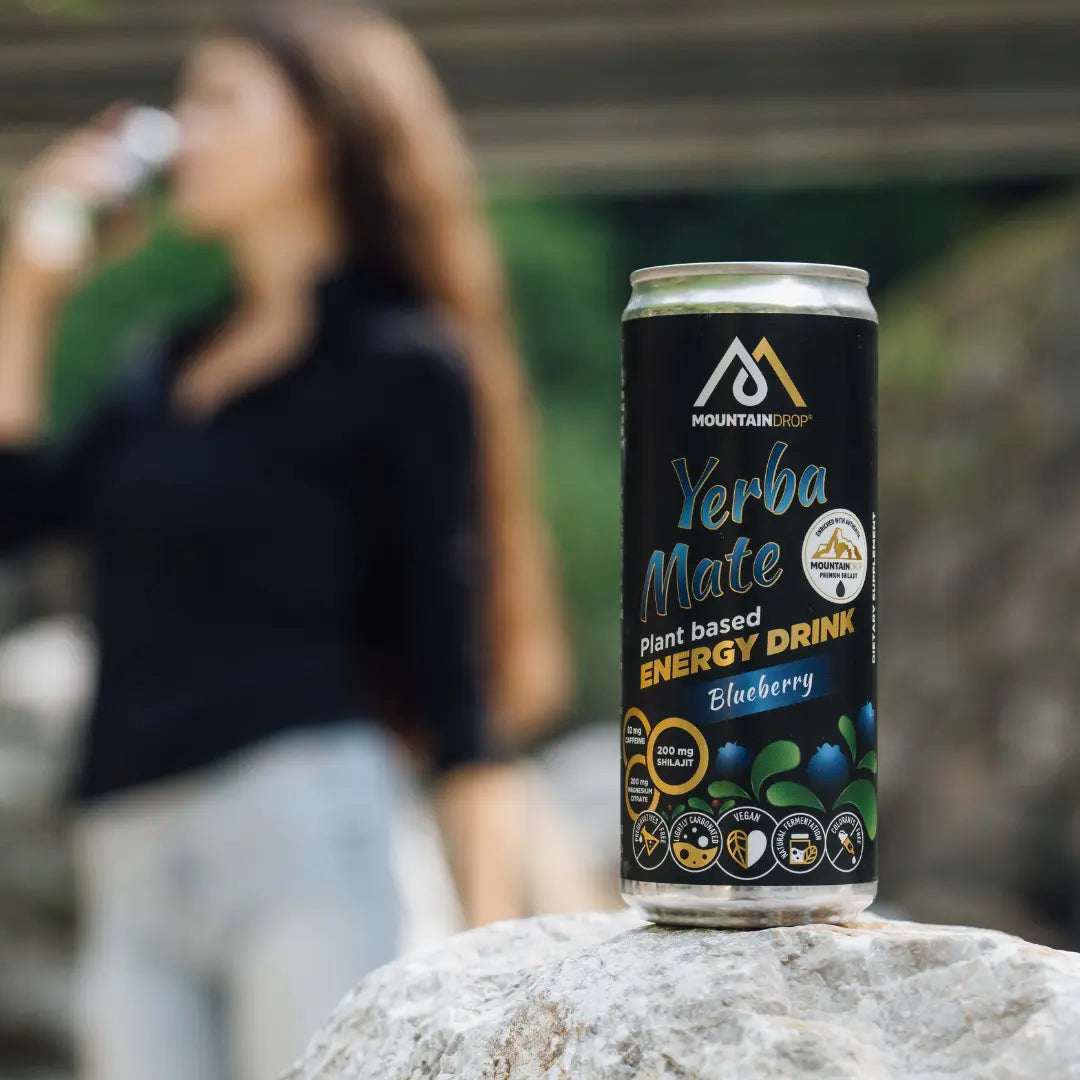 Nainen pitelee Mountaindrop Yerba Mate -juomaa ulkona – terveellinen energiajuoma luonnosta.