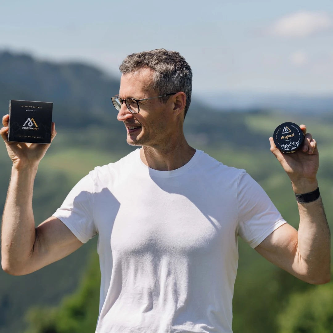 Mies pitelee Mountaindrop Shilajit -purkkeja ulkona – luonnollinen energian ja suorituskyvyn tuki.