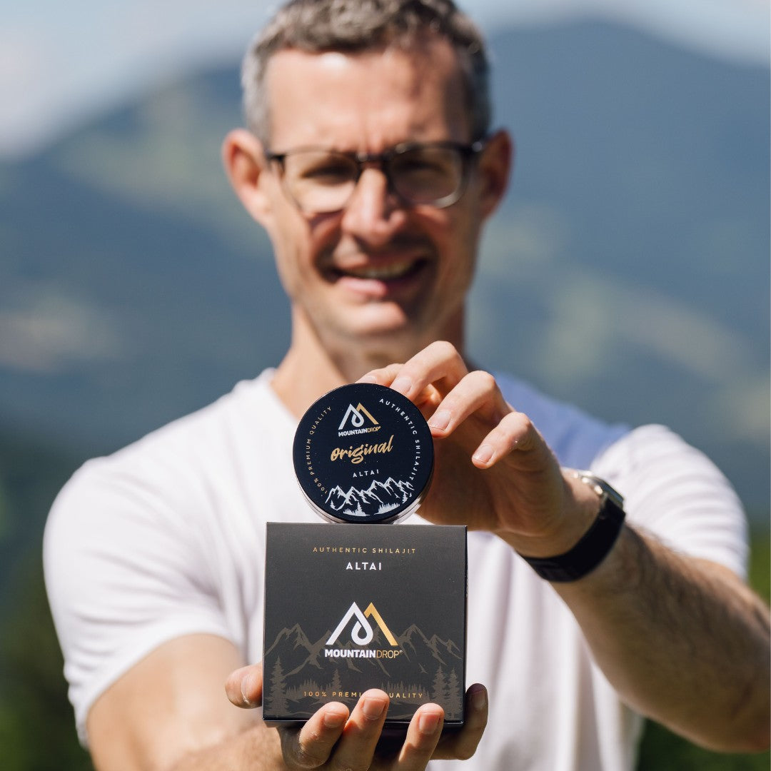 Mies pitelee kahta Mountaindrop Shilajit Altai -purkkia ulkona – luonnollinen tuki suorituskykyyn